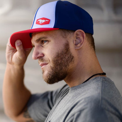 Man wearing a blue and red cap with a MUSTANG logo, looking to the side.