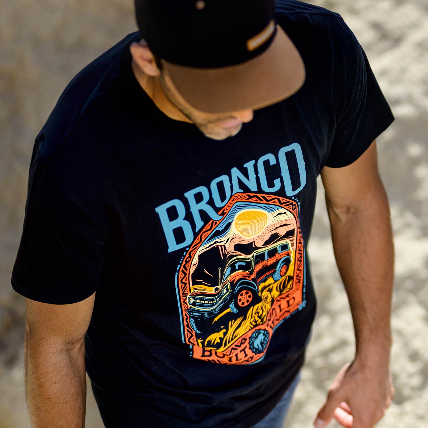 Person wearing a black t-shirt with 'Bronco' graphic design.
