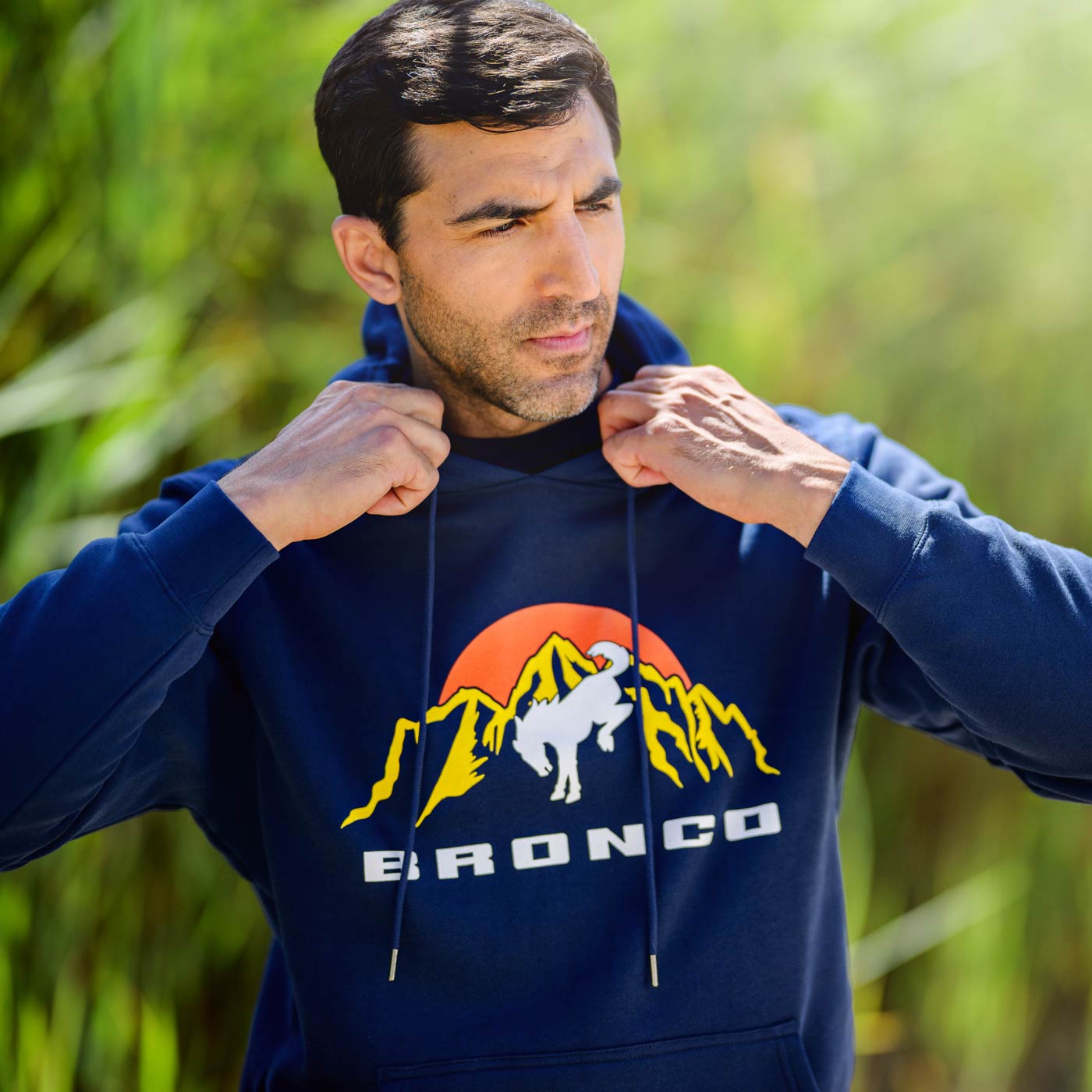 Man wearing a blue hoodie with a Bronco logo outdoors