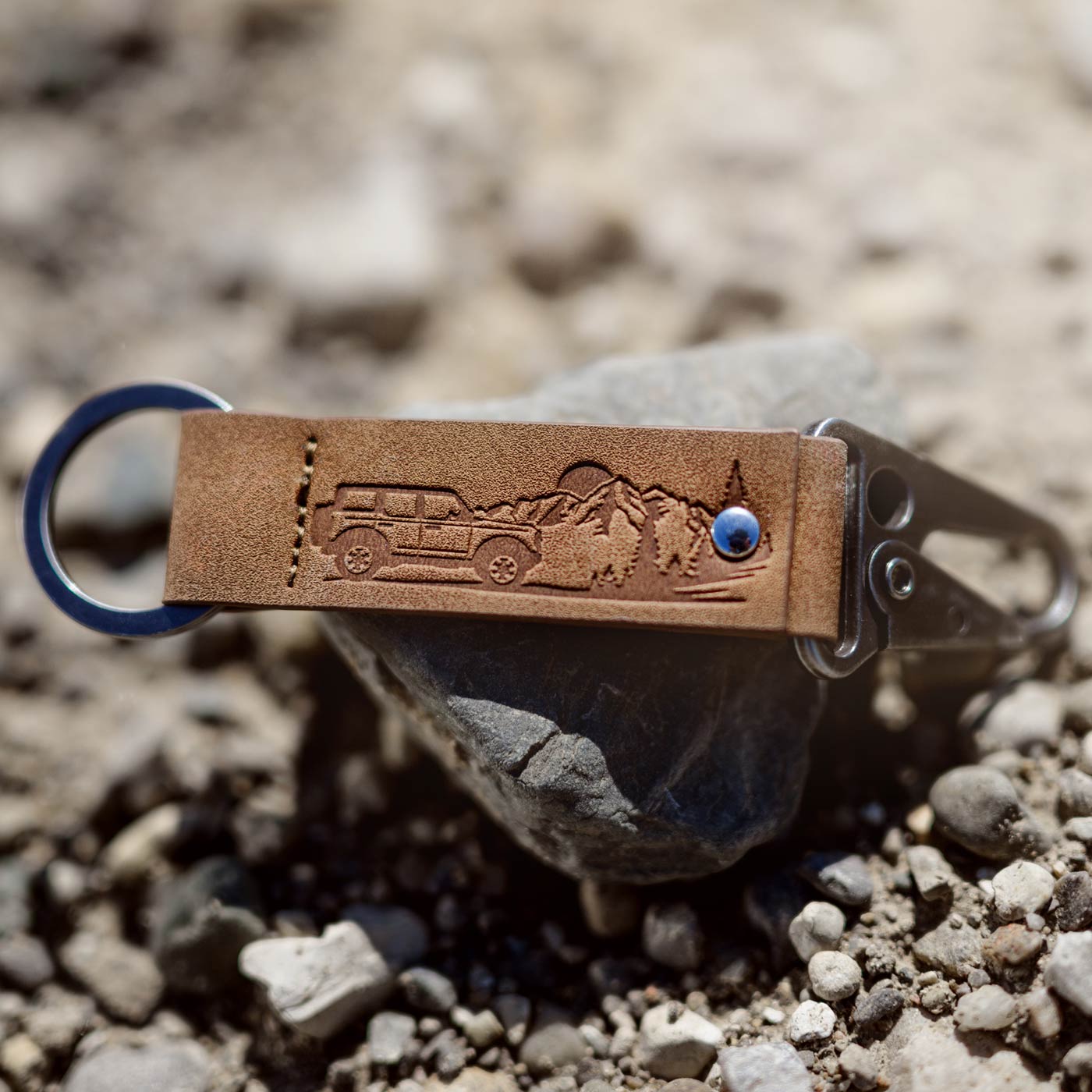 Brown leather keychain with embossed design on a rock