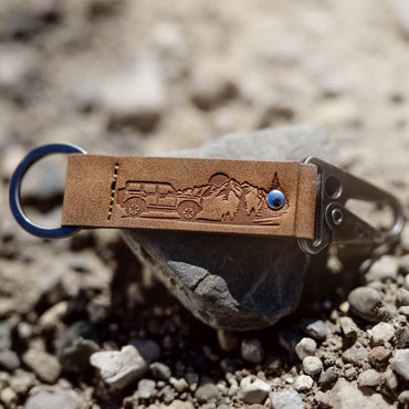 Brown leather keychain with embossed design on a rock