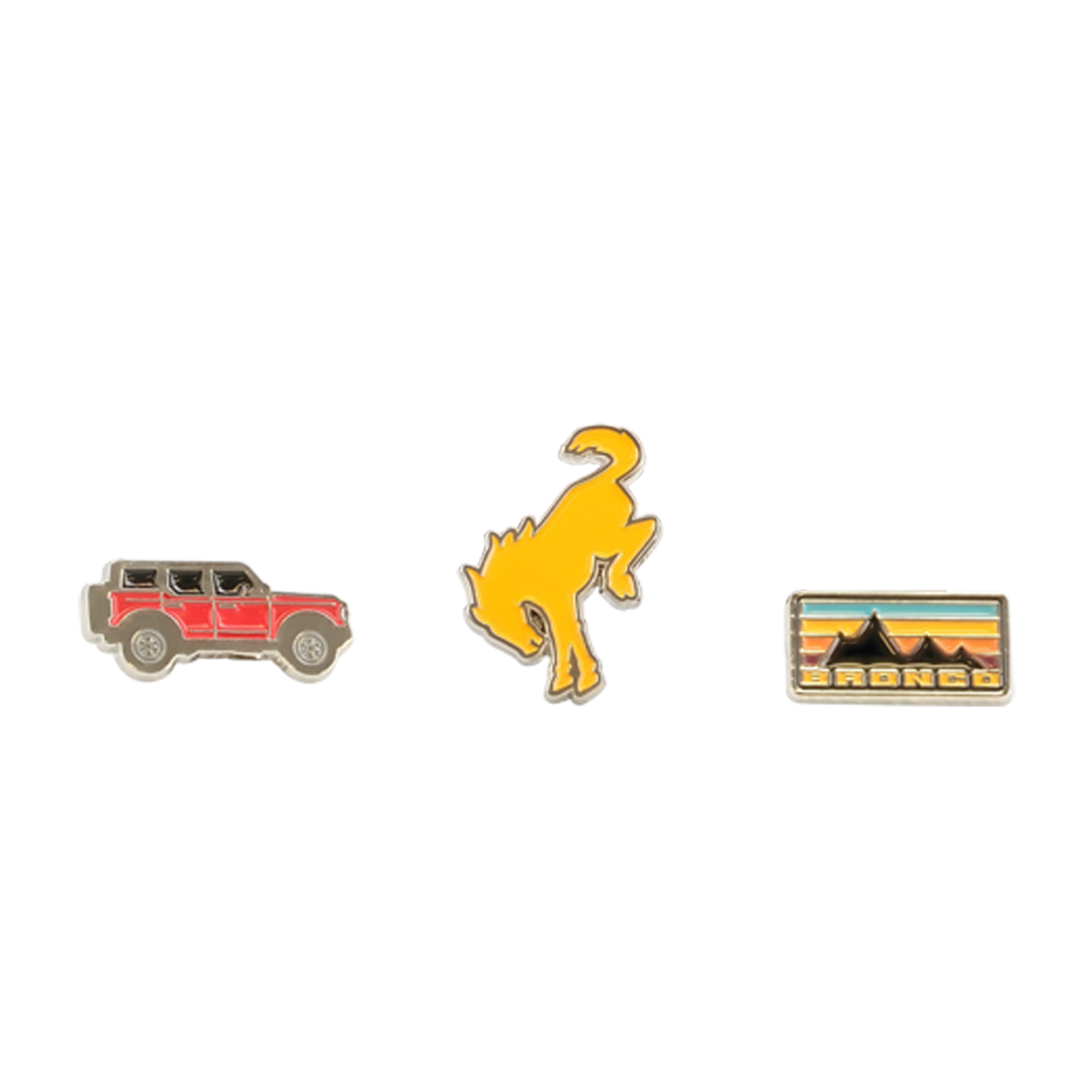 Three enamel pins on a white background: a red car, a yellow dinosaur, and a rectangular badge with mountains and text.