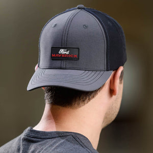 Person wearing a gray cap with a Ford Maverick logo on a blurred background