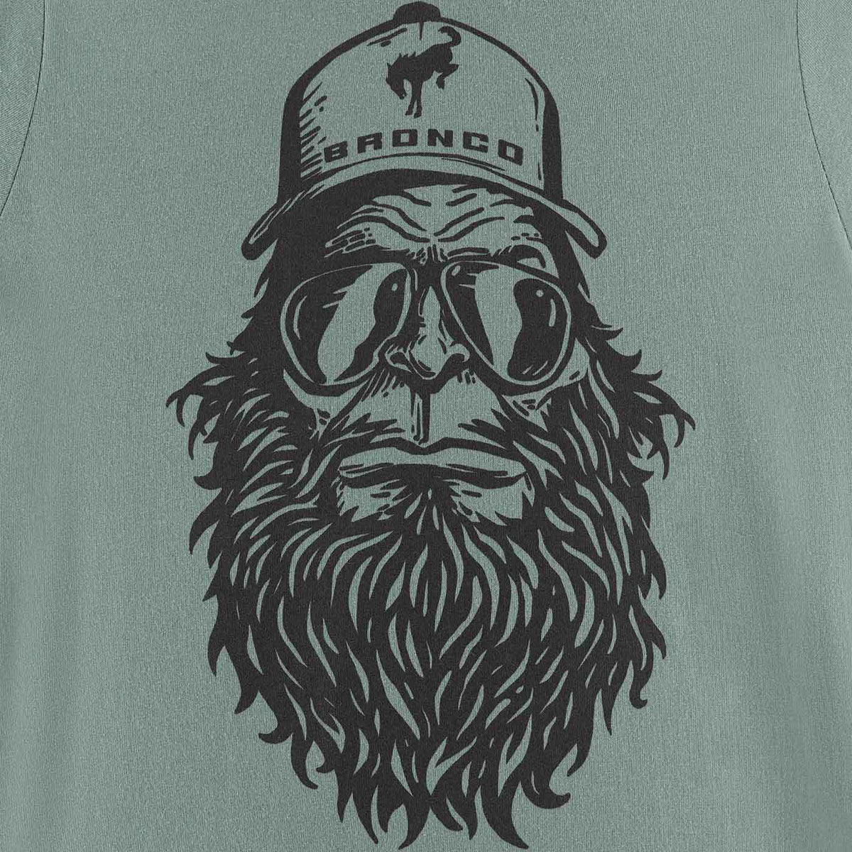 T-shirt with a graphic of a bearded man wearing goggles and a 'Bronco' cap on a green background