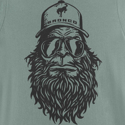T-shirt with a graphic of a bearded man wearing goggles and a 'Bronco' cap on a green background