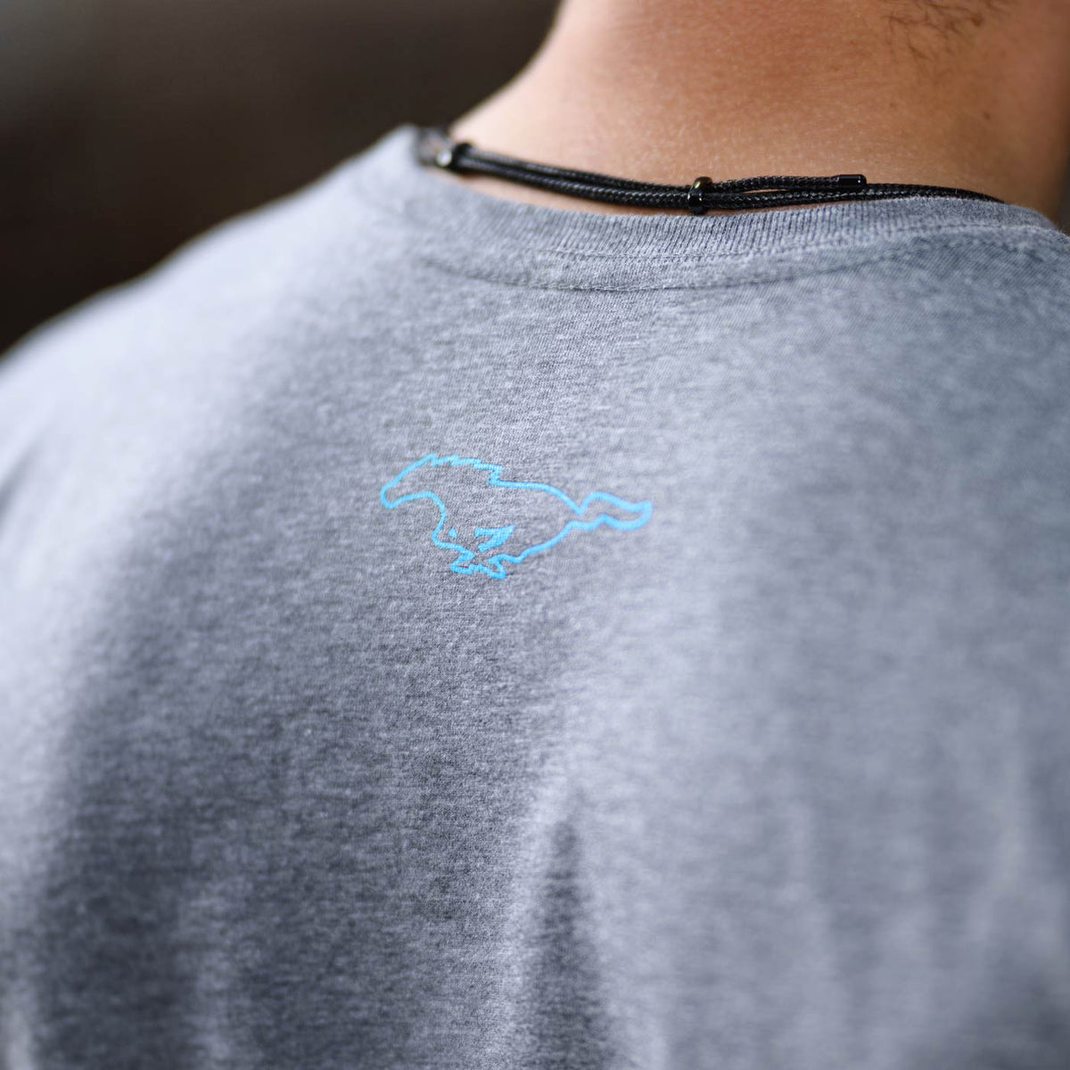 Gray t-shirt with a blue mustang pony logo on the back collar