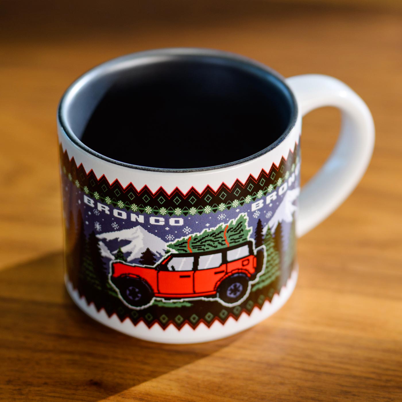 Mug with a festive design of a red bronco and Christmas tree on a wooden surface