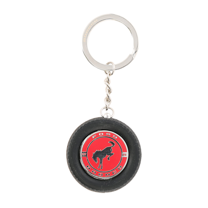 Keychain in the shape of a small tire with a red center and logo on a white background