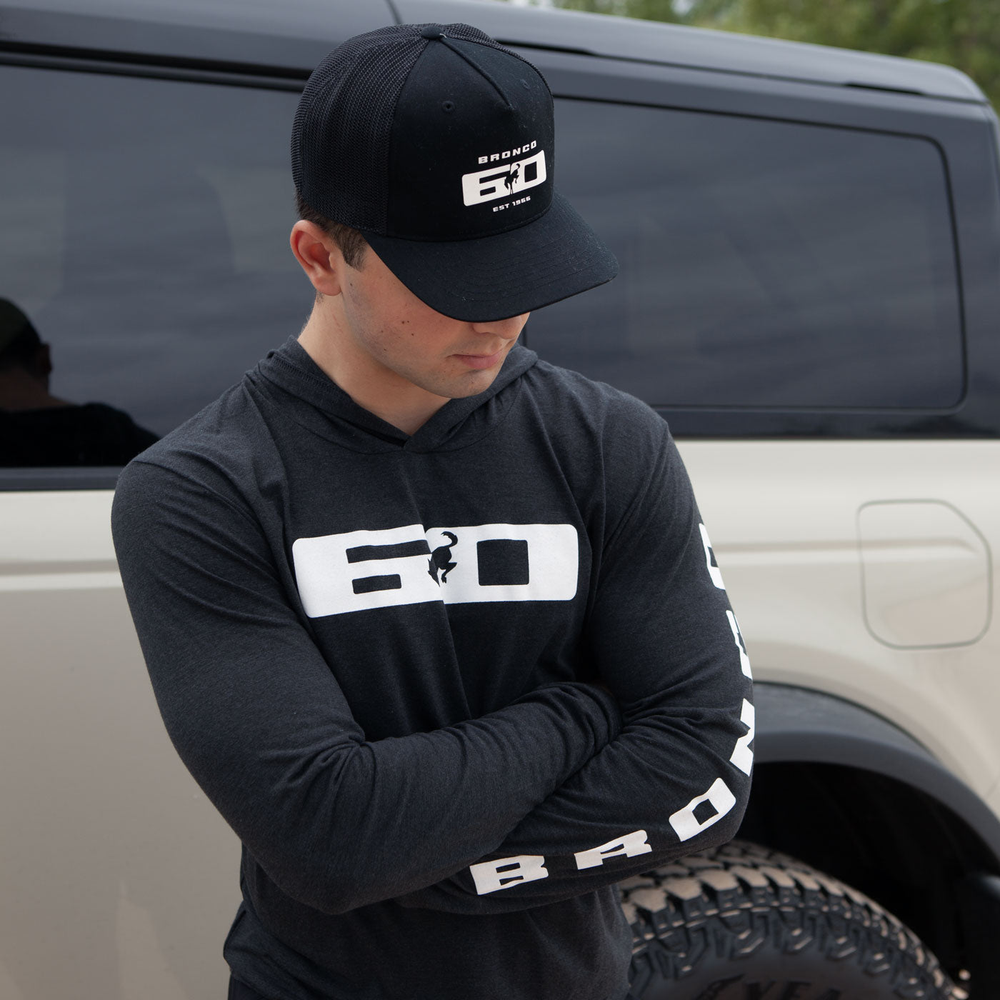 Person wearing a black hoodie and cap with '6.0' branding, standing in front of a truck.