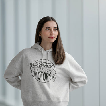 Woman wearing a gray hoodie with Ford Motors logo against a light gray curtain background