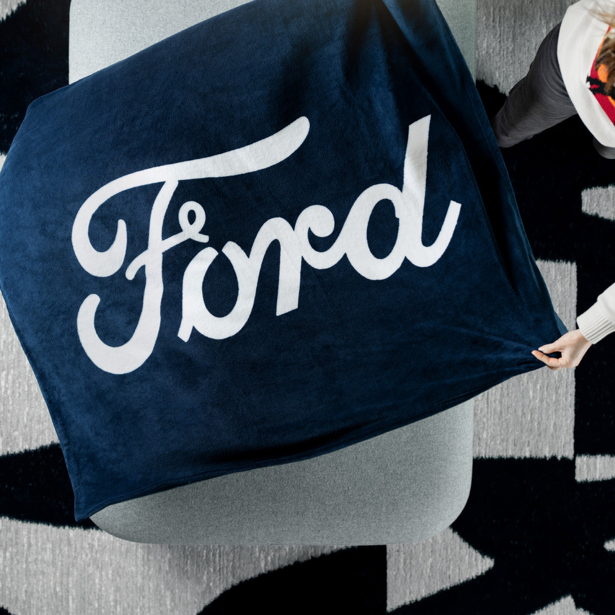 Navy blue towel with 'Ford' logo on a mannequin against a black and white patterned background
