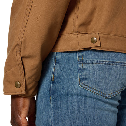 Close-up of a person wearing a tan work jacket with a buttoned cuff and a brown leather belt, paired with blue jeans.