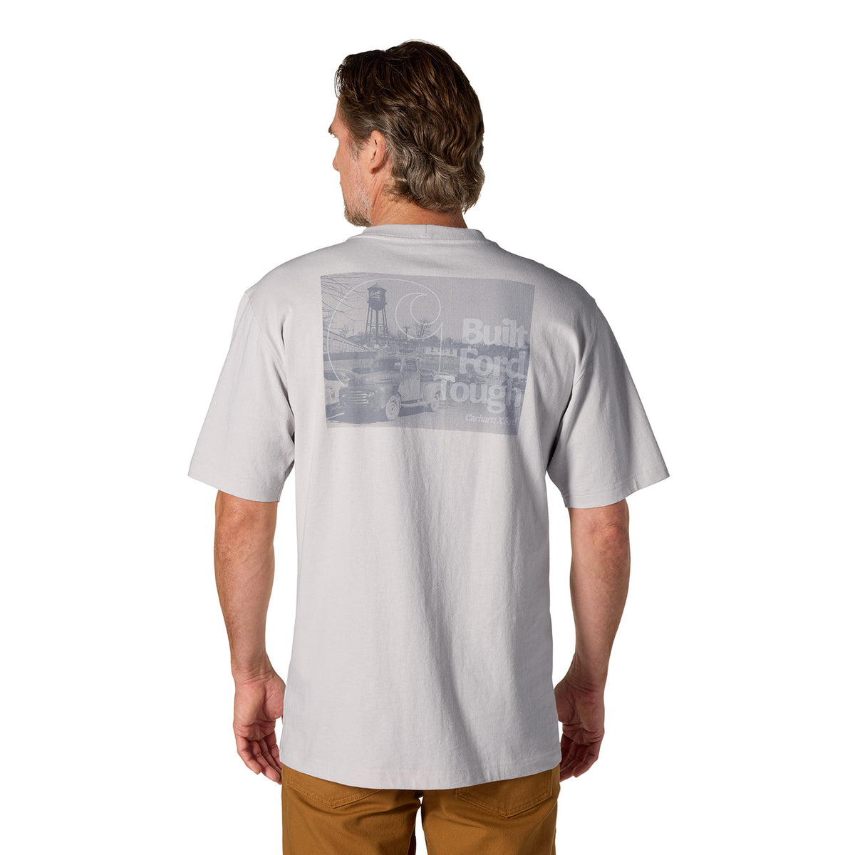A man viewed from the back wearing a light gray short-sleeve t-shirt with a faded gray graphic on the upper back that reads 'Built Ford Tough' and 'Detroit'.