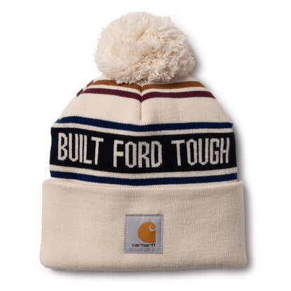 A cream-colored knit pom-pom beanie hat featuring navy, burgundy, and gold stripes, a black band with white text reading 'BUILT FORD TOUGH', and a gray Carhartt logo patch on the cuff.