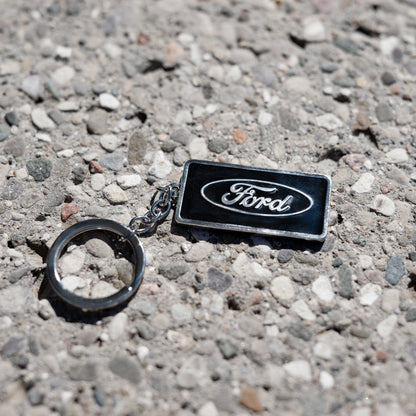 ford blue oval keychain on a pebbled background