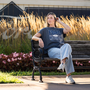 woman sitting on a bench in a ford motor co t-shirt