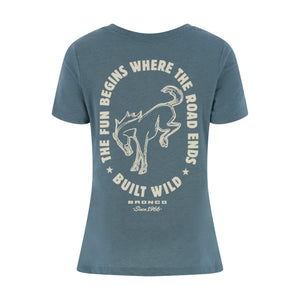 A slate blue short-sleeve t-shirt with a vintage-style cream graphic on the front. The graphic features a bronco outline surrounded by the text 'THE FUN BEGINS WHERE THE ROAD ENDS' and 'BUILT WILD', with 'BRONCO Since 1966' printed below.