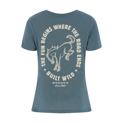 A slate blue short-sleeve t-shirt with a vintage-style cream graphic on the front. The graphic features a bronco outline surrounded by the text 'THE FUN BEGINS WHERE THE ROAD ENDS' and 'BUILT WILD', with 'BRONCO Since 1966' printed below.