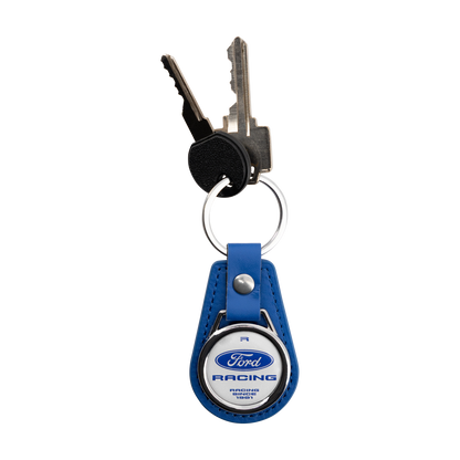 A blue leather keychain with a silver metal ring holding two keys, featuring a circular Ford Racing emblem on the front.