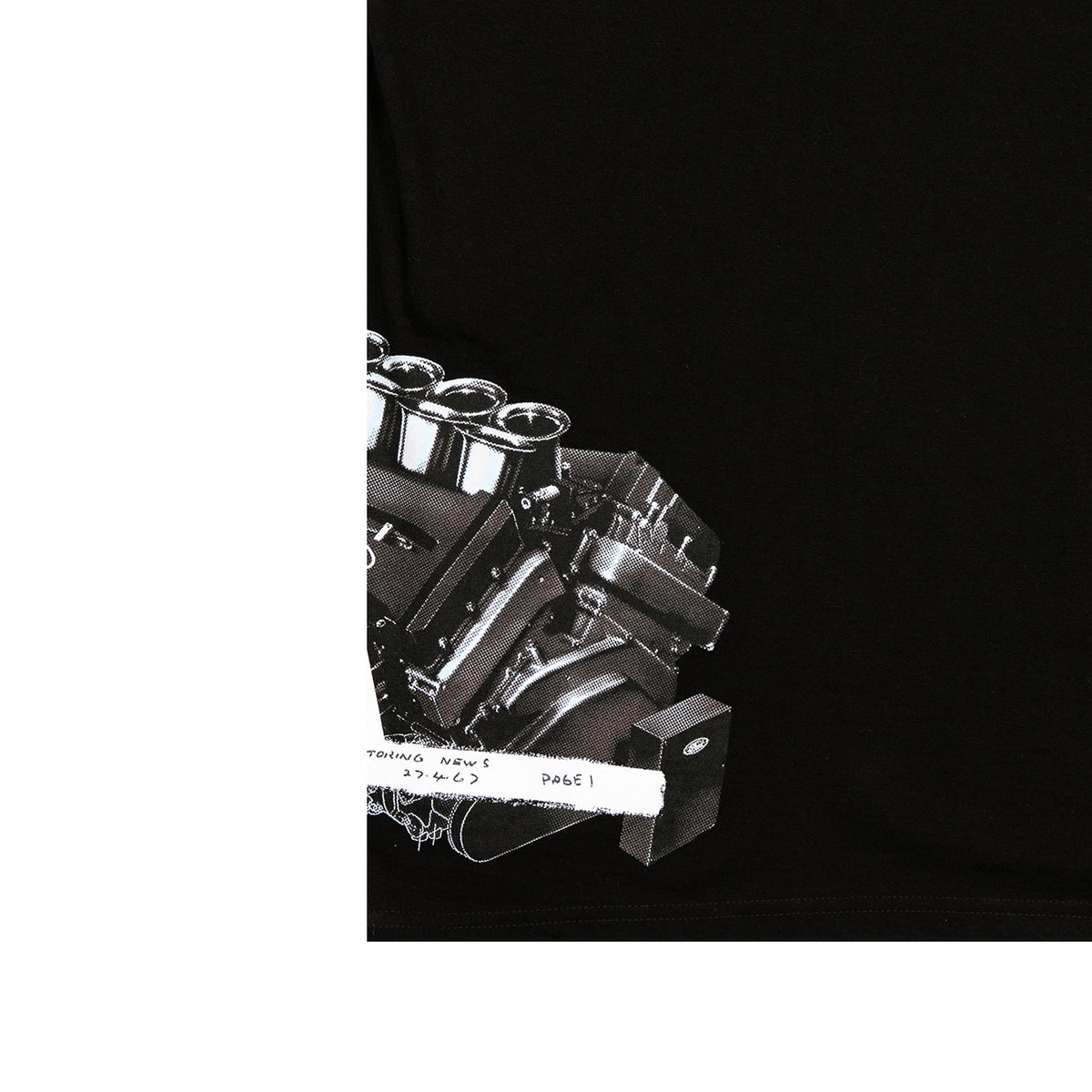 A close-up of a black garment, likely a t-shirt, featuring a detailed black and white graphic print of a V8 engine block with chrome valve covers and a white distressed label overlay.
