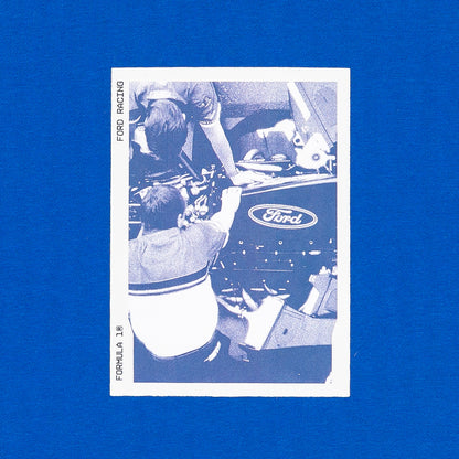 A vintage-style Ford racing collectible card featuring a blue-and-white photo of race drivers working around a car, displayed on a solid blue background.