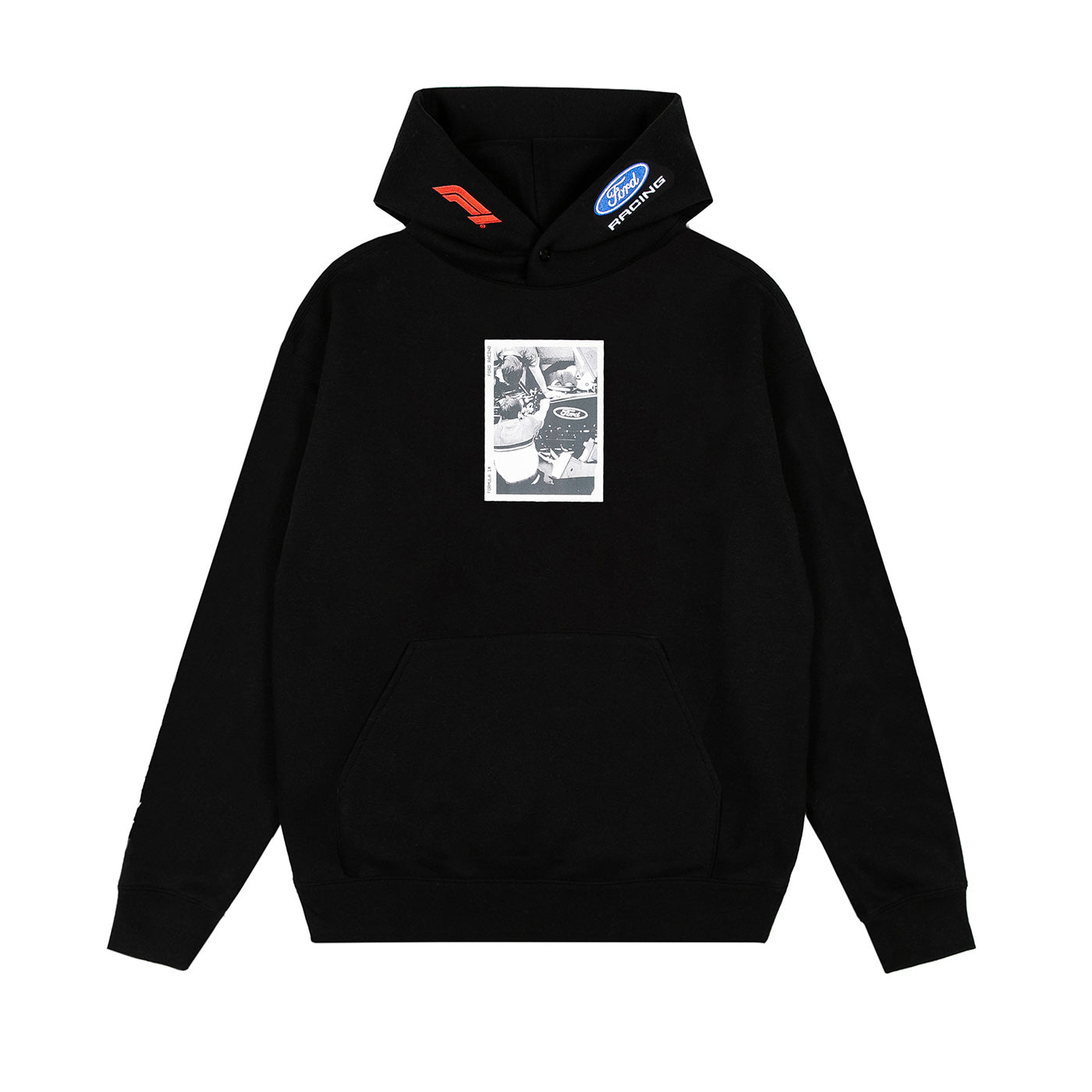 A black pullover hoodie with a kangaroo pocket, featuring a rectangular black-and-white graphic print on the chest and small red and blue logo patches on the hood.