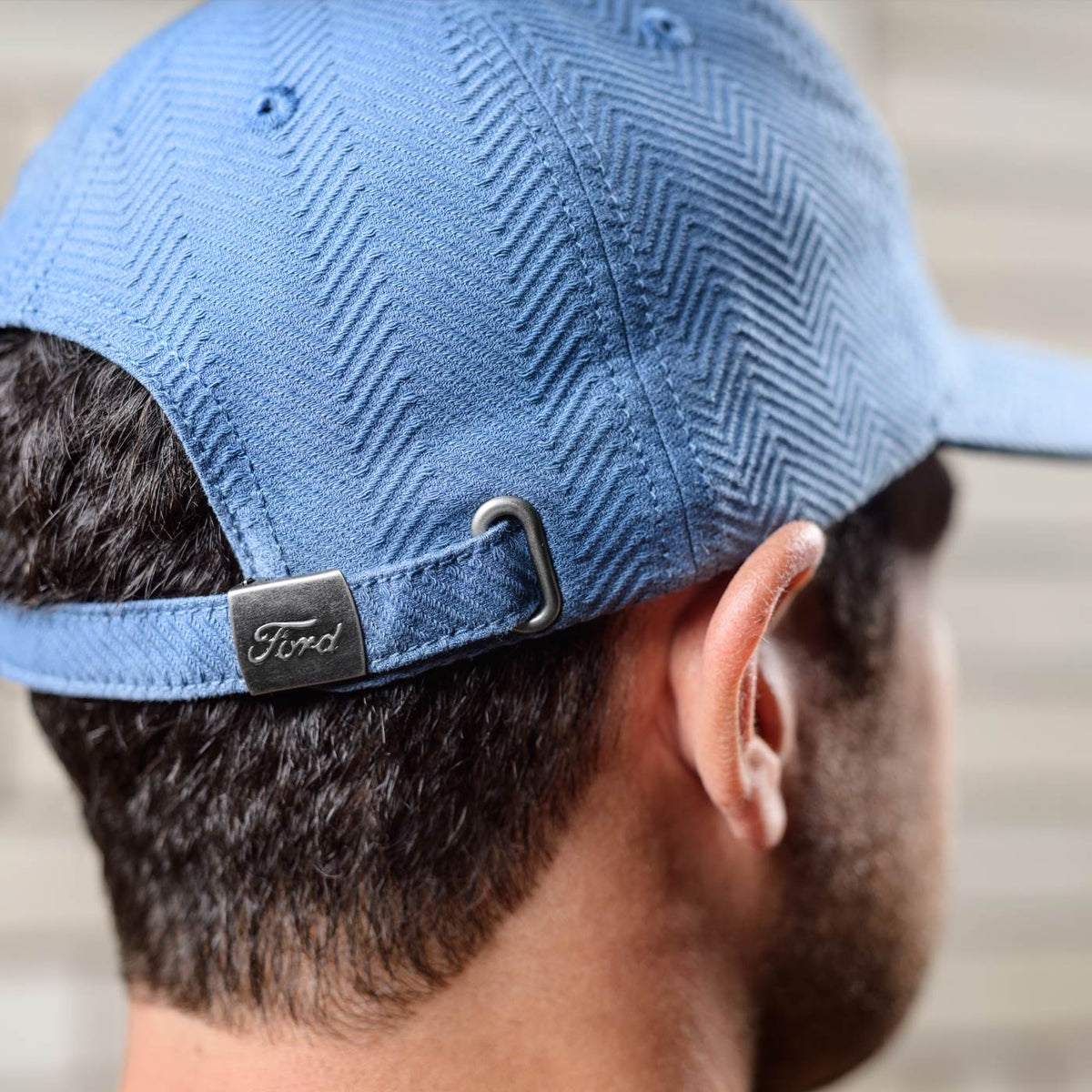 Blue cap with a Ford logo on the back worn by a person