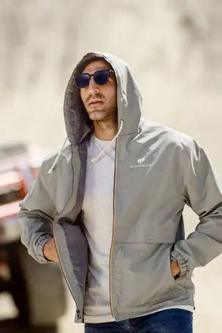 Man wearing a Ford Bronco gray hooded rain jacket with sunglasses on a blurred street background