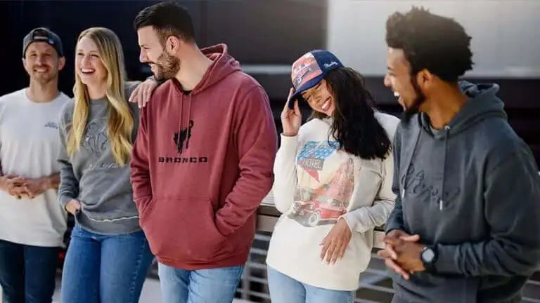 Group of five people standing together, smiling and interacting, with a focus on casual clothing and accessories.