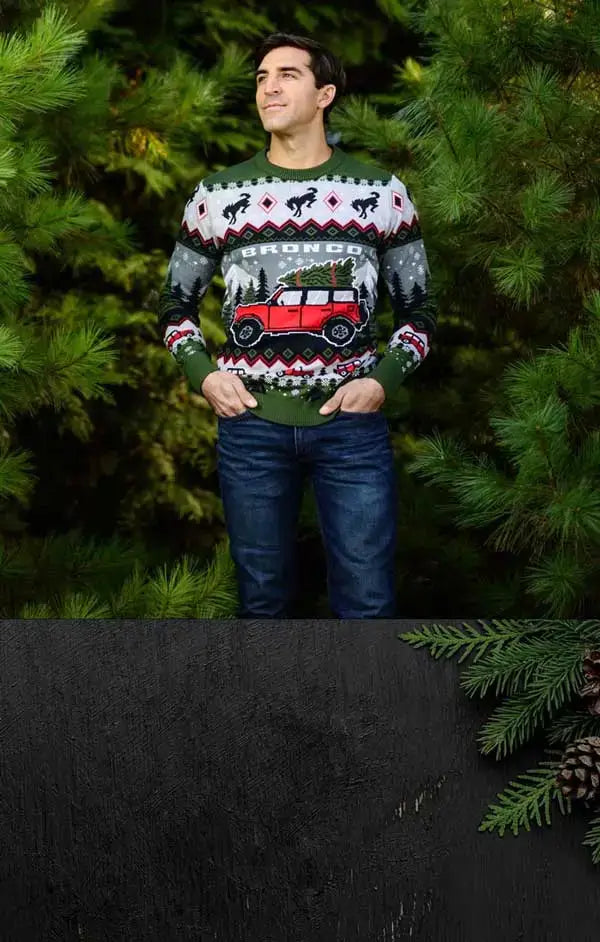Man wearing a festive sweater with a red car design in a forest setting