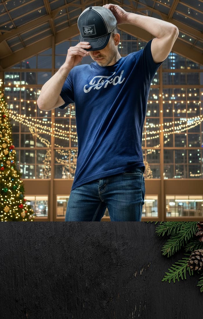 Man wearing a blue 'Ford' t-shirt and black cap indoors with festive decorations.