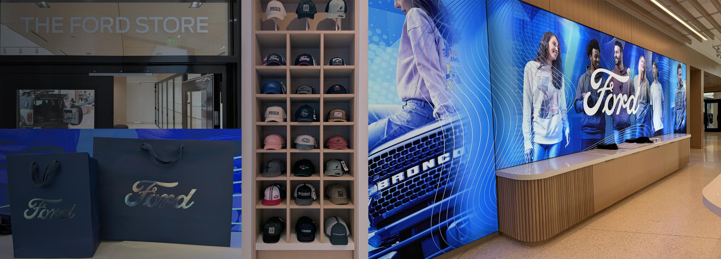 Ford retail store interior with a large blue Ford-branded wall display, a tall shelving unit filled with baseball caps, and a blue Ford shopping bag and box in the foreground.