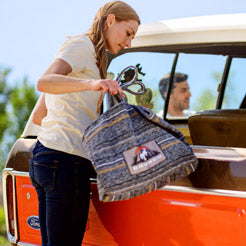 Woman placing a Ford Bronco tote bag with a patch on it into an orange vintage Bronco vehicle.