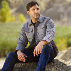 Man sitting on a rock with a scenic background wearing a Ford Bronco jacket