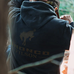 Person wearing a jacket with 'Bronco Wilson' branding, standing outdoors.
