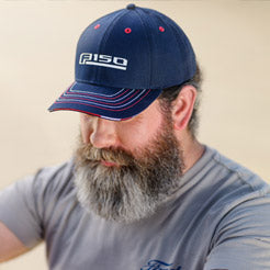 Man wearing a navy blue Ford F-150 hat, sitting outdoors.
