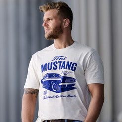 Man wearing a white t-shirt with Ford Mustang graphic t-shirt against a gray curtain background