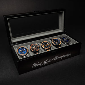Set of five watches in a display case with 'Ford Motor Company' branding on a dark background